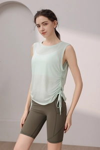 Detail view of a pale green yoga tank top with side drawstring and high-waist biker shorts