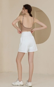 Gros plan sur le soutien-gorge de sport marron dos nu et le short blanc taille haute