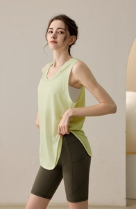 Close-up of a light green loose yoga tank top with functional side pocket on biker shorts