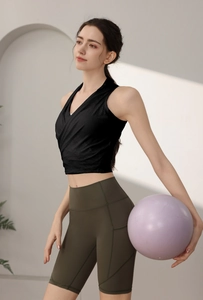 Top yoga nero slim fit con pantaloncini fitness verdi a vita alta e palla da ginnastica viola