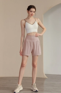Short de fitness rose 2 en 1 et brassière blanche pour femme dans un décor de studio moderne