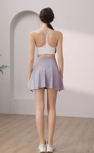 Vista posteriore di una gonna da tennis a pieghe lilla e reggiseno sportivo bianco sul retro