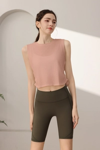Dettaglio crop top sportivo rosa senza maniche e pantaloncini verdi a vita alta con cuciture