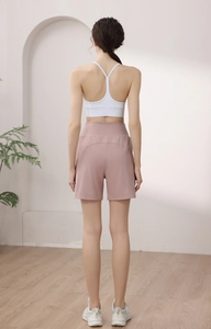 Detail of high-waisted pink sports shorts showing curved seam design for fit