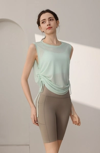 Detail of mint green mesh tank top with side drawstring and grey biker shorts with pockets