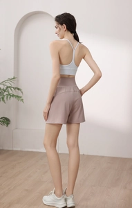Rear view of white thin-strap sports bra and pink high-waist yoga shorts in a studio