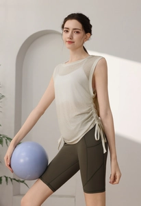 Detail of beige mesh yoga tank top with side drawstring and deep green biker shorts