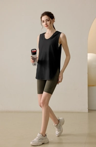 Women's loose black hooded fitness tank top with side slits shown on walking model