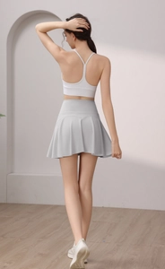 Vista posteriore del reggiseno sportivo bianco e gonna da tennis a pieghe grigia