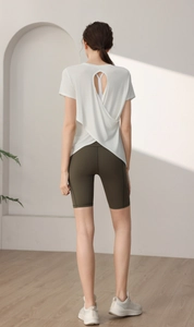Back view of a white modal yoga top featuring a crossover open back design and olive shorts