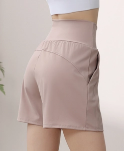 Macro shot of high-waist rose pink yoga shorts featuring side pockets and curved seam