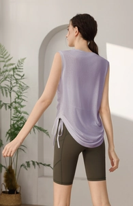 Detail view of a lavender yoga tank top with side drawstrings and green fitness shorts