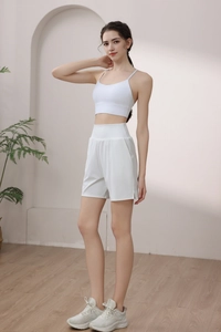 Side view of white high-waisted nylon sports shorts and matching bra in a studio setting