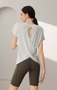 Detail showing the overlapping crisscross back and teardrop cutout of the white modal yoga top