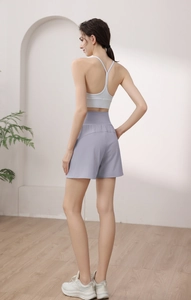 Detail view of the high-waist lilac yoga shorts with cross-strap white sports bra and sneakers