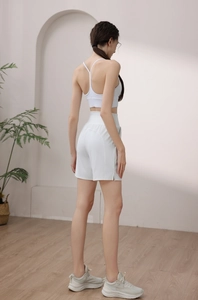 Side view of white high-waist yoga shorts and strappy sports bra on a model