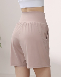 Detail view of high waisted fitness shorts with side pockets in dusty rose pink fabric