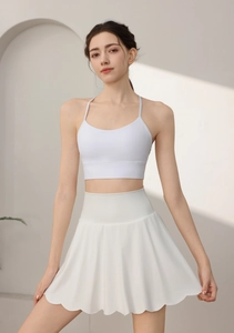 Detailed view of white high-waisted petal yoga skirt and cross-strap sports bra