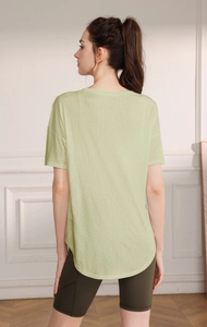 Détail du haut de yoga ample vert clair avec ourlet incurvé respirant et coupe décontractée