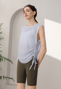 Detail of light blue yoga vest with side drawstring ruching and olive green bike shorts