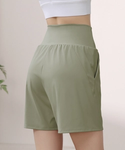 Close-up of high-waisted sage green sports shorts showing side pockets and elastic fabric