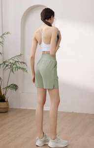 Detail of high-waisted light green athletic shorts with side slit and curved stitching