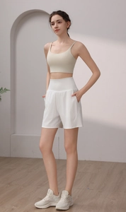Detail of a beige crop sports bra and white high-waist loose athletic shorts on a model