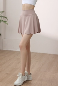 Detail view of pink high-waisted pleated tennis skirt with scalloped edge hem and soft fabric