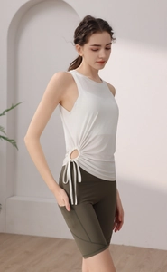 Detail of white yoga tank top with side drawstring cutout and olive green cycling shorts