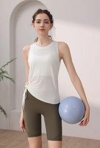 Detail of white sports tank top with side drawstring ties and olive green yoga shorts