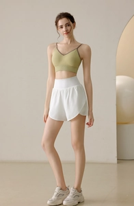 Detail of high-waist white sports shorts and avocado green sports bra on a model