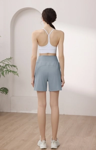 Rear view of high-waisted light blue yoga shorts and white tank top set on model