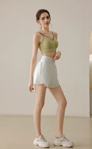 Close-up of olive green sports vest and white high-waist shorts for fitness and yoga