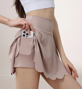 Detail view of pink yoga skirt featuring a side pocket for phone storage and wavy hem