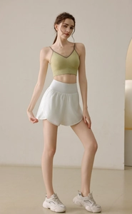 Detail view of high-waist loose white sports shorts and green crop top for yoga