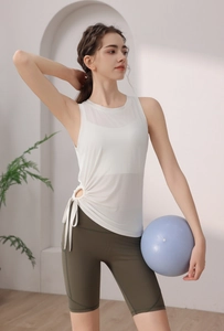 Detail of white yoga tank top with side drawstring ruching and high waist green shorts