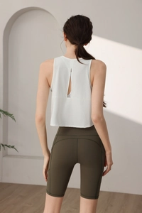 Détail du débardeur de sport blanc avec découpe au dos et legging de yoga vert olive