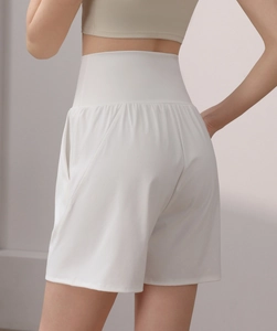 Detail of high-waisted white sports shorts featuring functional side pockets and loose fit