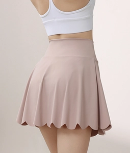 Detail of high waisted mauve yoga skirt with scalloped hem and pleated athletic fabric