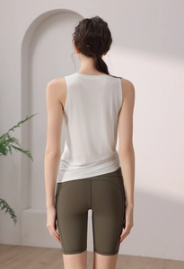 Rear view of a white sleeveless yoga tank top paired with olive green cycling shorts