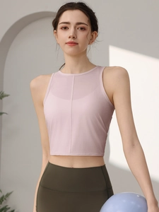 Enges rosa Yoga-Top und olivgrüne Leggings mit einem Yogaball in einem hellen Raum