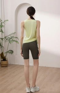 Detail of light yellow yoga tank top with side drawstring ruching and green cycling shorts