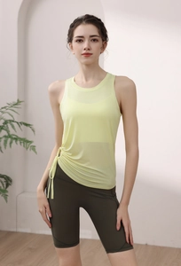 Detail of pale yellow yoga top with side drawstring design and green gym shorts