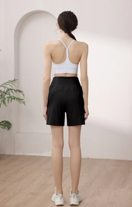 Rear view of loose high-waist black sports shorts and white yoga bra on a female model
