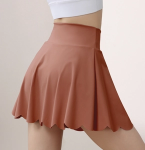 Detail of high waisted cinnamon tennis skirt with unique scalloped hem and stretchy fabric