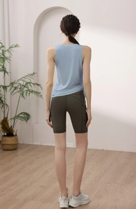 Back view of yoga set featuring light blue drawstring tank top and olive green cycling shorts