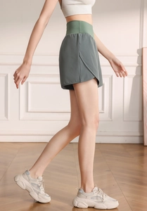 Detail view of high-waisted sage green sports shorts with side slits for women