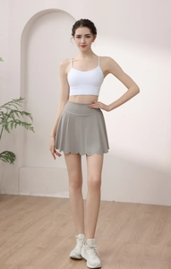 Detail of high-waist grey tennis skirt with ruffle petal hem and white yoga tank top