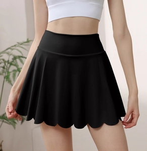 Detail of high-waisted black tennis skirt showing the scalloped hem and pleated design