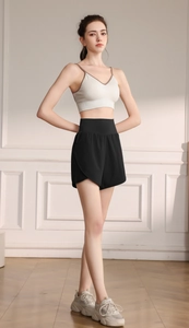 Close-up of white sports bra and black high-waisted loose fitness shorts on model